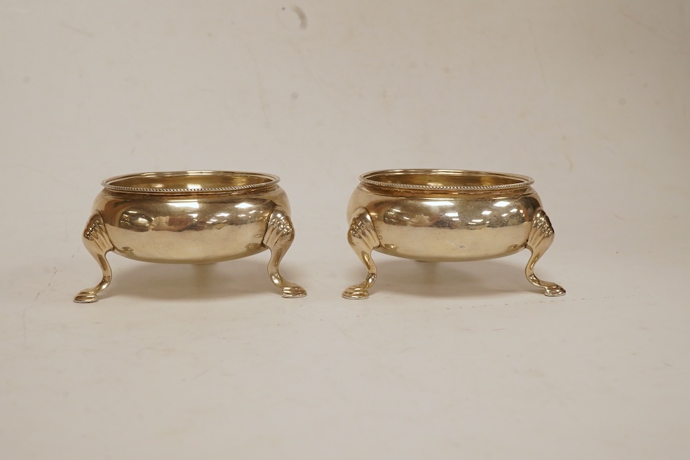 A pair of George II silver bun salts, Edward Wood, London, 1741, diameter 58mm, together with an Eastern white metal mounted cigarette box and a white metal crotal? bell. Condition - poor to fair